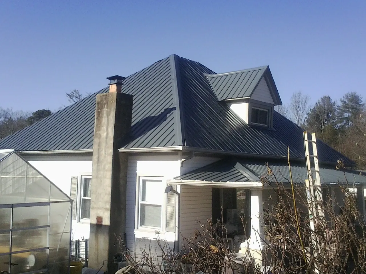 Dark blue standing seam metal roof on a white farmhouse with dormer — Slate & Tile Roof Repair by Roofing Brothers in Guilford