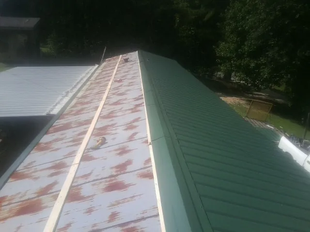 Old rusted panels beside newly installed green metal roofing — Wind Damage Roof Repair by Roofing Brothers in Guilford